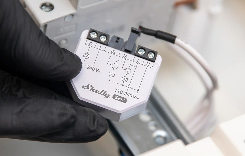 Sterownik SHELLY EM Gen3 Wi-fi Bluetooth, moc, energia, temperatura, wilgotność, dłoń trzyma sterownik przed montażem do szyny DIN