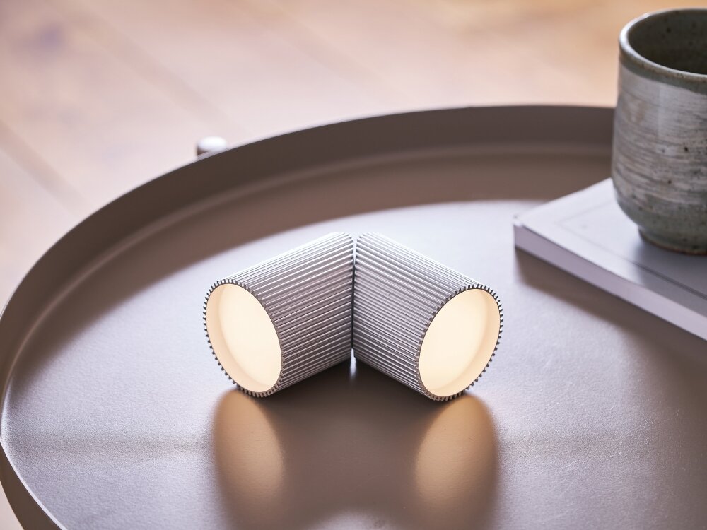 Lampka LEXON Ray Light Aluminium (2 szt.) moc w detalu srebrne lampki leżą na stoliku żebrowana faktura