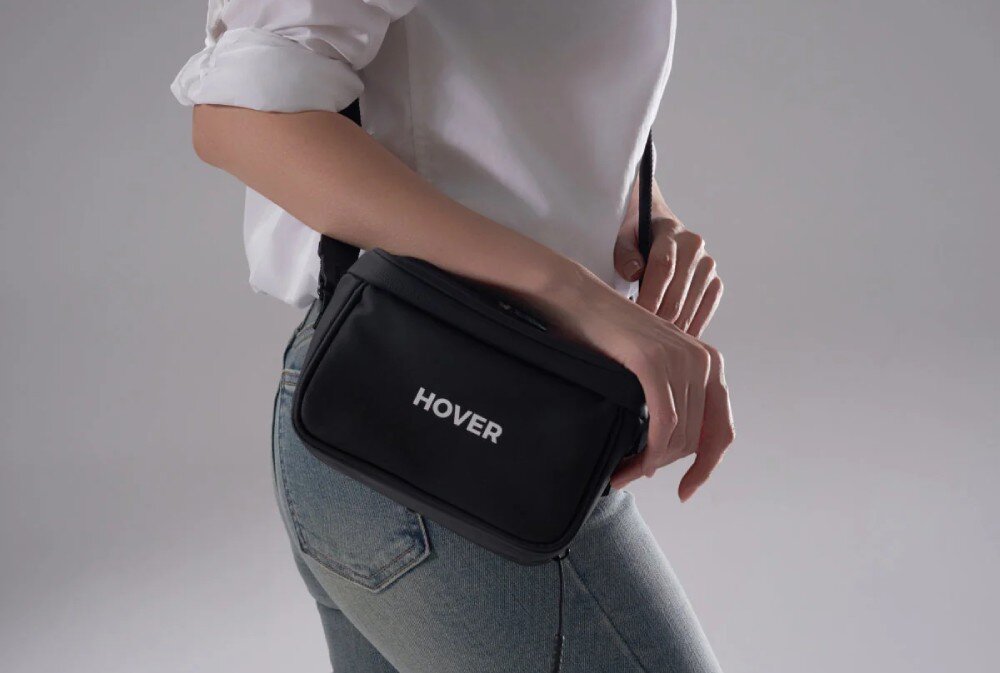 Torba HOVERAIR Multi-functional Carry Bag Kobieta w białej koszuli z czarną torbą na pasku widoczna z profilu, pasek na ramię, przeznaczenie