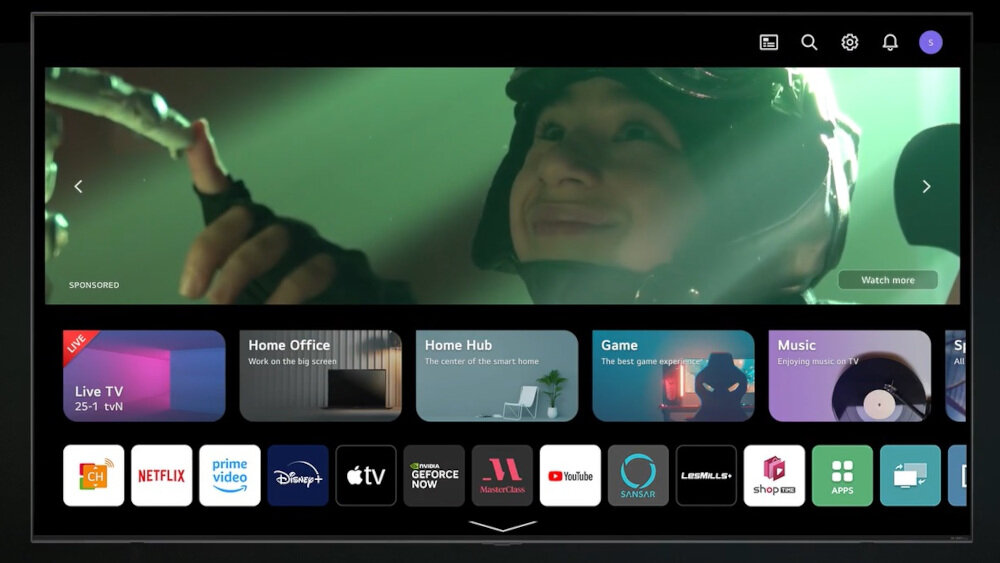 Ekran telewizora wyświetla interfejs z aplikacjami takimi jak Netflix, Prime Video, Disney+, Apple TV, YouTube i inne. W tle widoczna jest scena z filmu z osobą w hełmie, a na dole ekranu znajdują się ikony aplikacji.