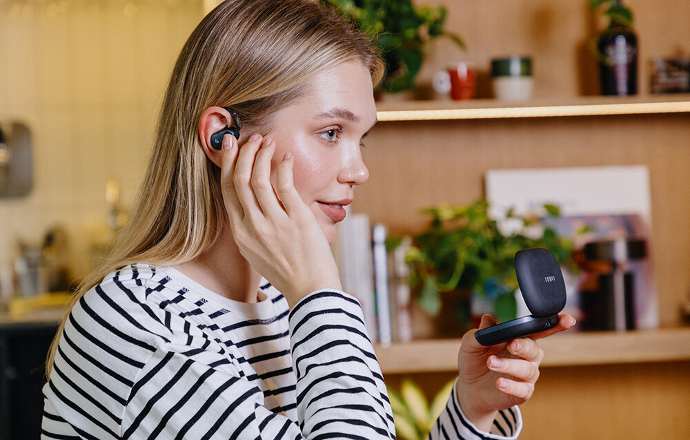 Słuchawki EDIFIER Comfo Flex przetworniki jakość dźwięku hi-res audio, osoba z założonymi słuchawkami trzymająca w ręku etui ładujące