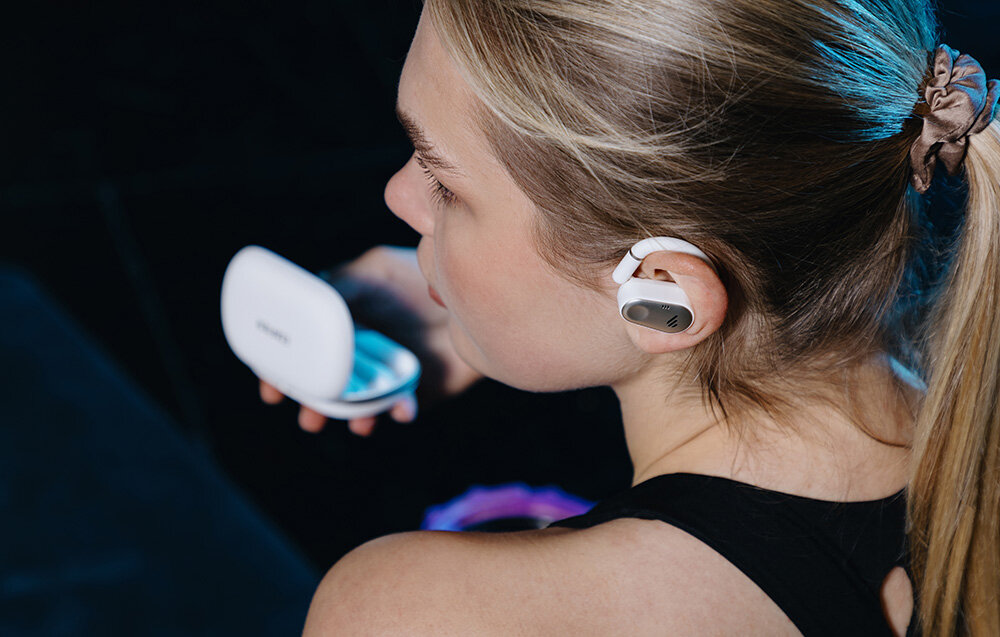 Słuchawki EDIFIER Comfo Flex bluetooth multipoint stabilne połączenie, osoba z założonymi słuchawkami trzymająca w ręku etui ładujące
