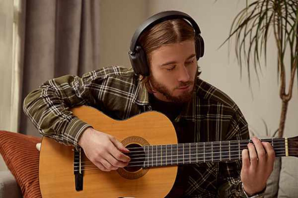 EDIFIER ES850NB ANC słuchawki Hi-Res Audio 40 mm tytanowa membrana LDAC SBC Bluetooth, osoba z założonymi słuchawkami nausznymi trzymająca gitarę w rękach