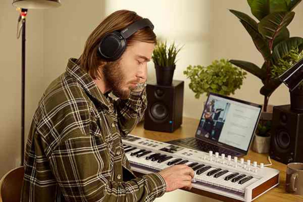 Słuchawki EDIFIER ES850NB ANC Bluetooth 5.4 multipoint connection Touch-to-chat przyciski silikonowe, osoba z założonymi słuchawkami nausznymi grająca na keyboardzie