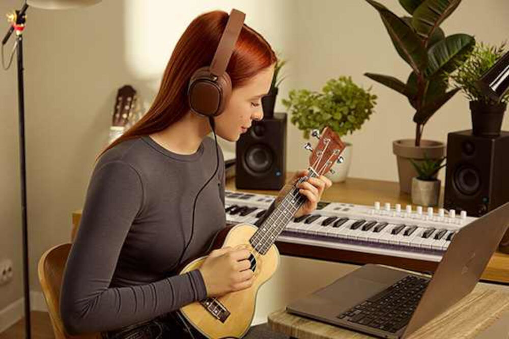 Słuchawki EDIFIER ES850NB ANC dwa mikrofony AI redukcja szumów czyste rozmowy Bluetooth, osoba z założonymi słuchawkami nausznymi trzymająca w ręku ukulele