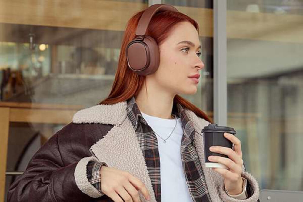 Słuchawki EDIFIER ES850NB ANC aplikacja ConneX tryby Spatial Sound Music Gaming Mode personalizacja dźwięku, osoba z założonymi słuchawkami nausznymi trzymająca kubek z gorącym napojem