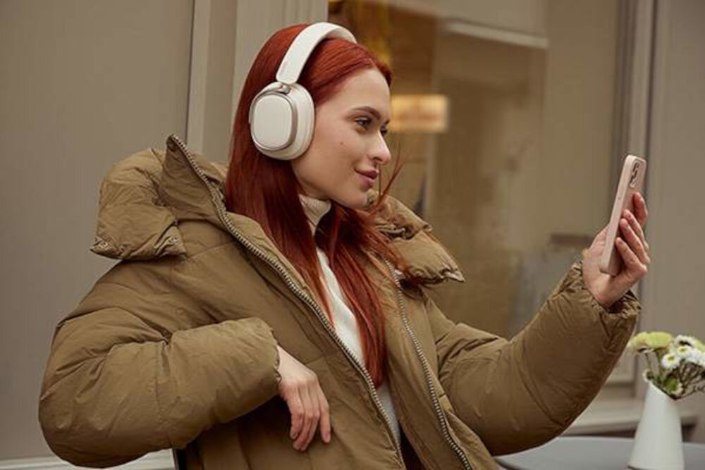 Słuchawki EDIFIER ES850NB ANC dwa mikrofony AI redukcja szumów czyste rozmowy Bluetooth, osoba z założonymi słuchawkami nausznymi trzymająca w ręku smartfona