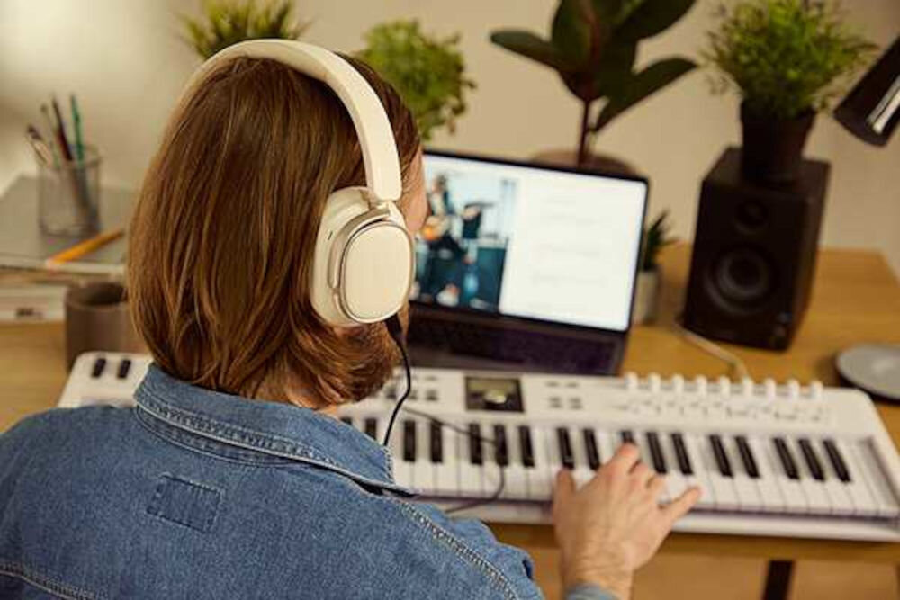 Słuchawki EDIFIER ES850NB ANC aplikacja ConneX tryby Spatial Sound Music Gaming Mode personalizacja dźwięku, osoba z założonymi słuchawkami nausznymi grająca na keyboardzie