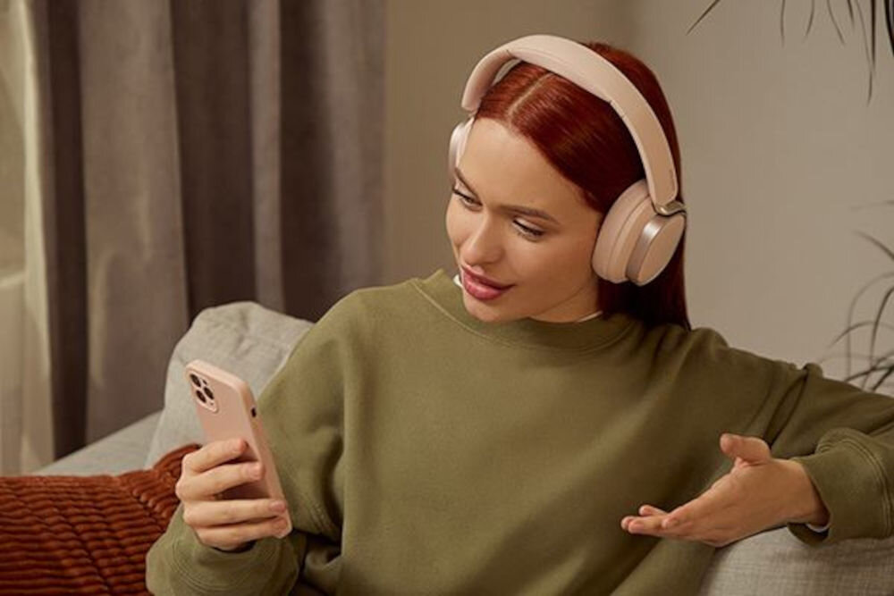 Słuchawki EDIFIER ES850NB ANC dwa mikrofony AI redukcja szumów czyste rozmowy Bluetooth, osoba z założonymi słuchawkami nausznymi trzymająca w ręku smartfona