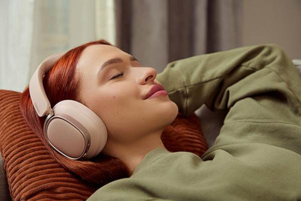 EDIFIER ES850NB ANC słuchawki składane czarne stalowy pałąk miękkie nauszniki pokrowiec ochronny, osoba z założonymi słuchawkami nausznymi leżąca na kanapie