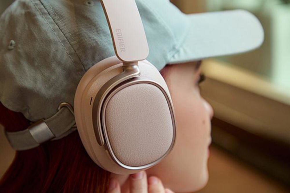Słuchawki EDIFIER ES850NB ANC aplikacja ConneX tryby Spatial Sound Music Gaming Mode personalizacja dźwięku, osoba w czapce z daszkiem z założonymi słuchawkami nausznymi