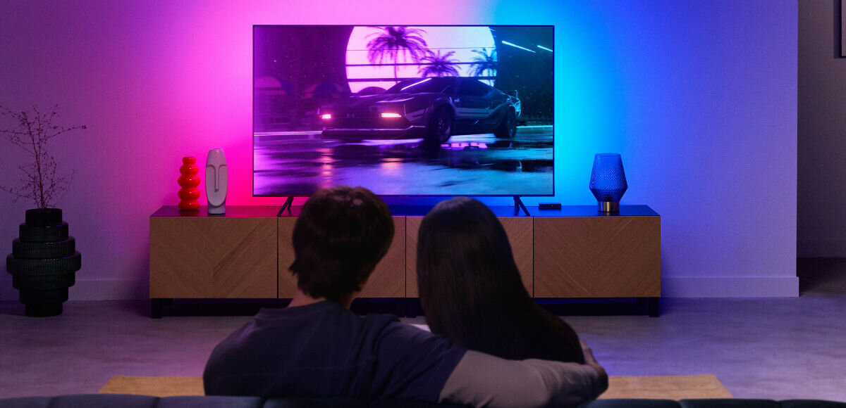 Taśma LED WIZ Sync Box do TV 55 - 65 2.6 m Wi-Fi, Zgraj światło z TV, Para siedzi przy telewizorze z włączona opcją LED WIZ