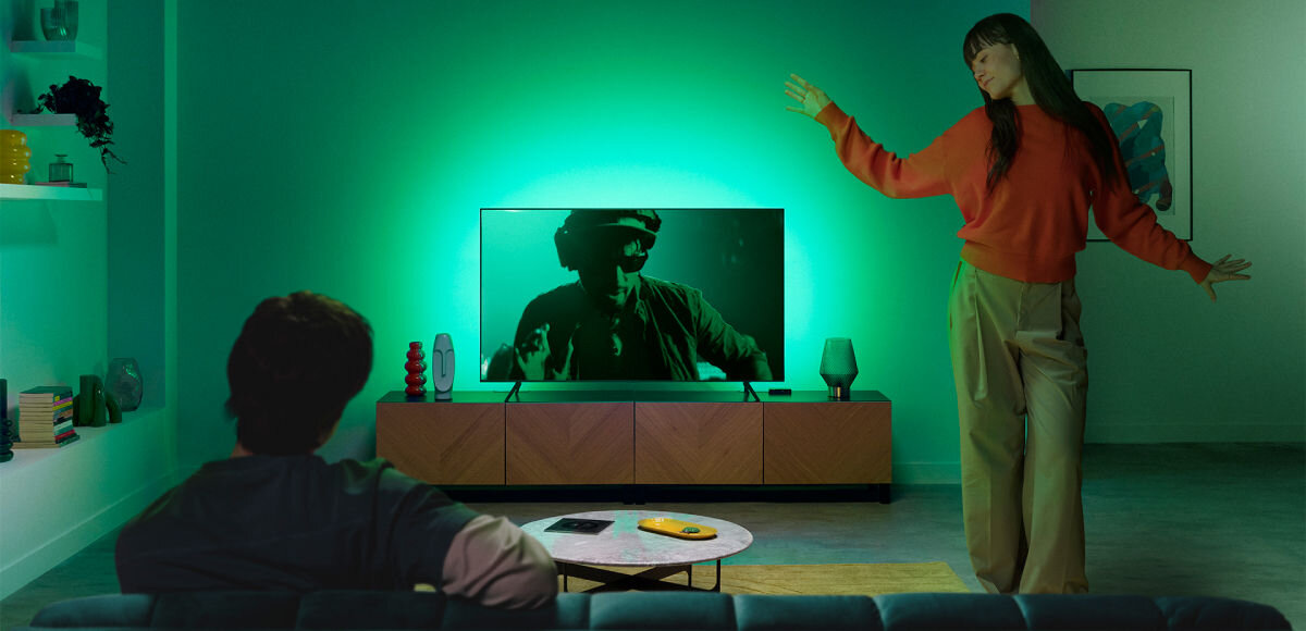 Taśma LED WIZ Sync Box do TV 55 - 65 2.6 m Wi-Fi, Światło na każdą okazję, Para w pokoju, kobieta tańczy a mężczyzna siedzi przy włączonym tv