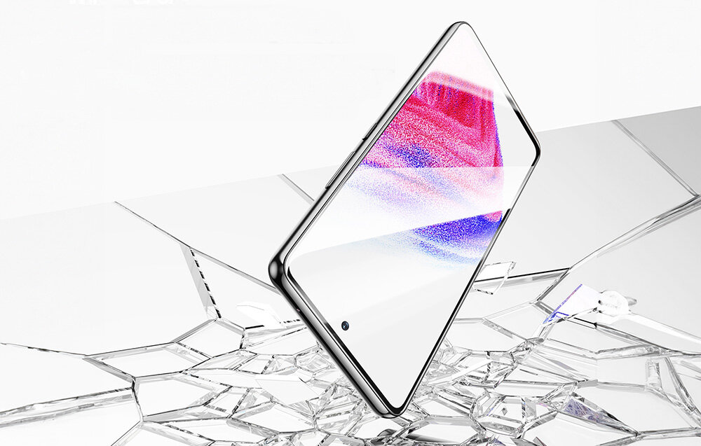 Smartfon z wyświetlaczem w kolorze różowo-niebieskim leży na powierzchni przypominającej rozbite szkło. Ekran jest włączony, a na nim widoczny jest gradientowy wzór.