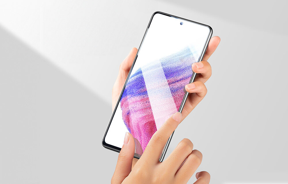 Osoba trzyma smartfon z kolorowym wyświetlaczem, na którym widoczne są abstrakcyjne wzory. Ekran jest dotykany palcem wskazującym.