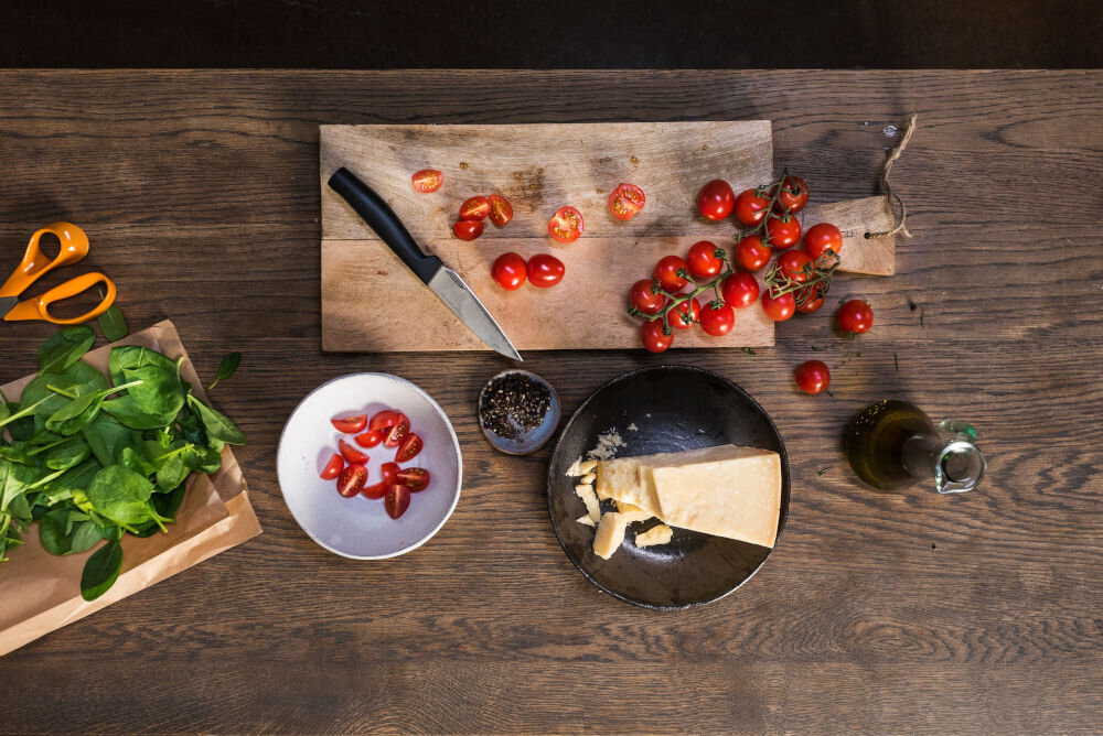 Nóż FISKARS Hard Edge 1051762 deska na desce leży nóż z czarną rączką obok leżą pomidorki dla każdego Ostrze o długości 10,9 cm całkowitej długości 22,8 cm krojenie obieranie waży jedynie 54 g