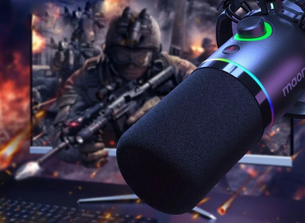 Mikrofon MAONO PD200XS Mikrofon w czarnej obudowie z czarną gąbką zamocowany w uchwycie antywibracyjnym na tle monitora z grafiką żołnierza