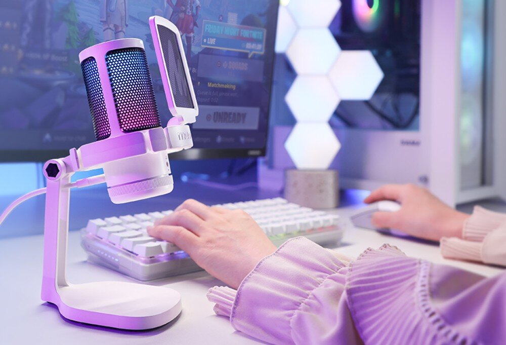 Mikrofon MAONO DGM20 Biały mikrofon na statywie z filtrem pop stoi na białym biurku obok białej klawiatury, a w tle widać monitor z grą oraz podświetloną obudowę komputera
