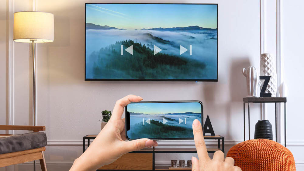 Odtwarzacz multimedialny 4K TESLA MediaBox XG500 Chromecast bezprzewodowe przesyłanie filmów i muzyki, telewizor zawieszony na ścianie w salonie, ręce trzymające smartfona