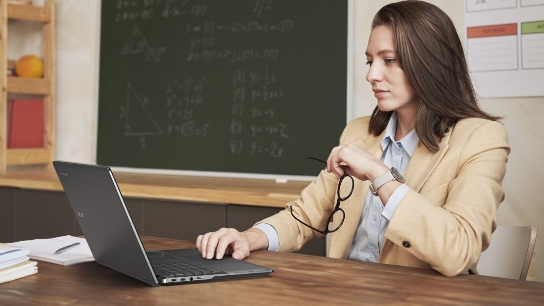 Kobieta w garniturze pracuje na laptopie, skupiona na ekranie, w biurowym otoczeniu. - System Chrome OS