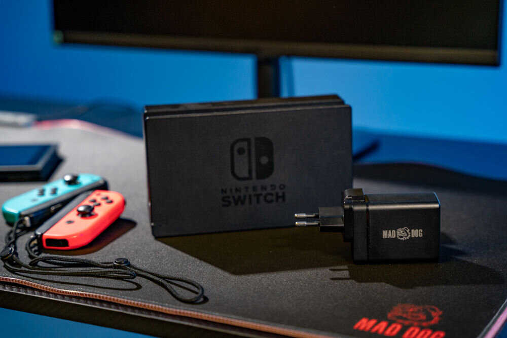 Ładowarka MAD DOG GCD600K włączona do gniazdka w tle monitor tablet i telefon podłączone kablami do ładowarki