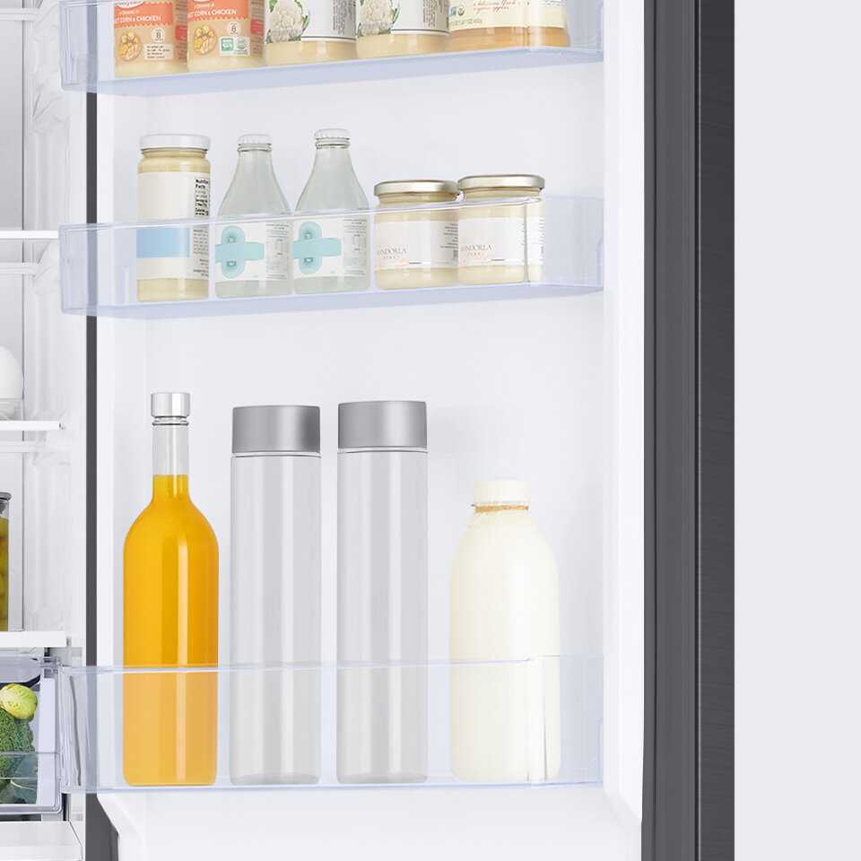 Słoiki, wysokie butelki z napojami umieszczone w 4 pojemnikach na drzwiach