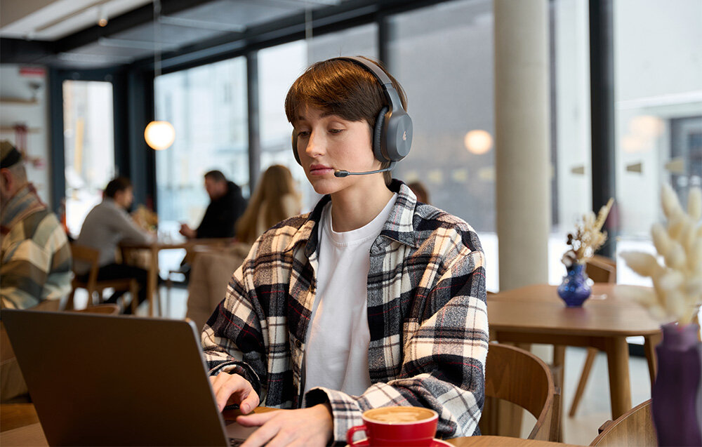 Słuchawki EDIFIER K750W bezprzewodowe nauszne komfort Bluetooth, osoba z założonymi słuchawkami pracująca na laptopie