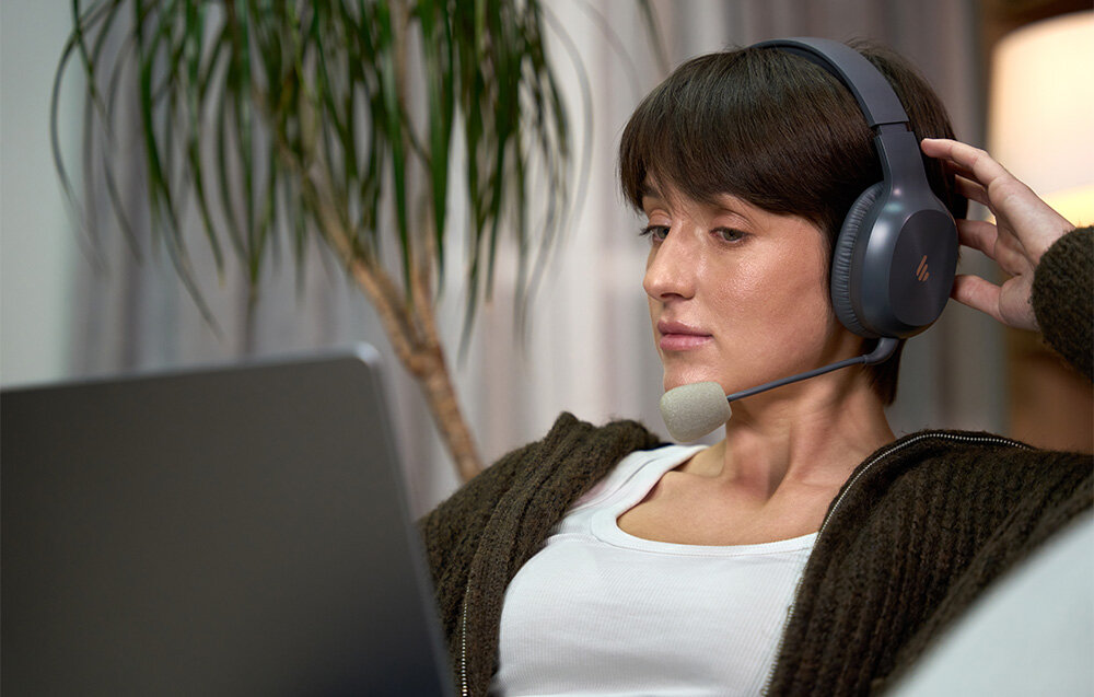 Słuchawki EDIFIER K750W nauszniki pianka komfort pałąk izolacja, osoba z założonymi słuchawkami nausznymi pracująca na laptopie