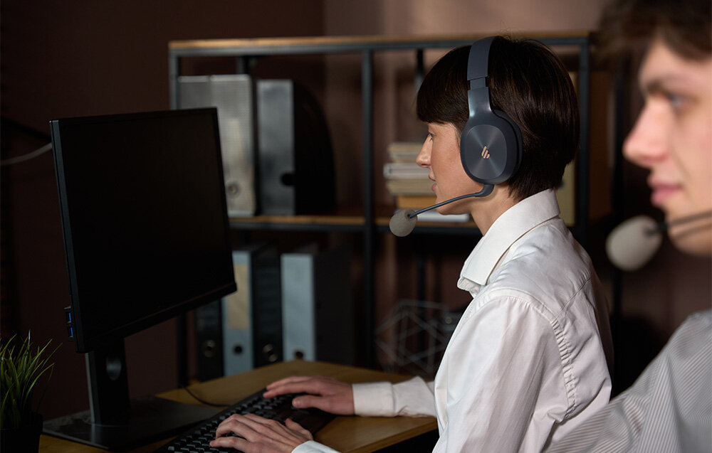 Słuchawki EDIFIER K750W Bluetooth 5.4 multipoint łączność stabilność, osoba z założonymi słuchawkami nausznymi pracująca przy biurku
