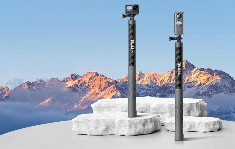 Dwa selfie sticki z włókna węglowego marki TELESIN stoją na białych, kamiennych platformach na tle górskiego krajobrazu. Na jednym z nich zamontowana jest kamera sportowa.