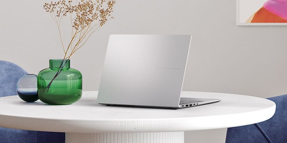 Laptop ASUS VivoBook S 14 na stole obok wazonu z kwiatami lub czarnej, żłobkowanej filiżanki . - Wzornictwo metaliczne wykończenie