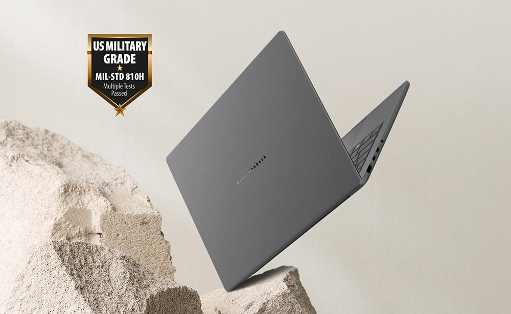 Laptop ASUS Zenbook 14 na tle kamienistego krajobrazu z certyfikatem MIL-STD 810H US Military Grade w lewym górnym rogu, demonstracja wojskowej odporności na ekstremalne warunki środowiskowe - Odporność na trudne warunki MIL-STD 810H