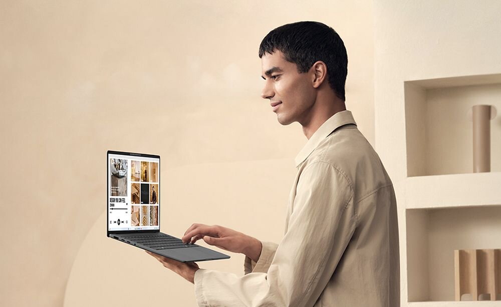 Mężczyzna w beżowej koszuli pracujący na laptopie ASUS Zenbook z kolorowym ekranem wyświetlającym mozaikę zdjęć w nowoczesnym minimalistycznym wnętrzu - Opis serii Zenbook A14