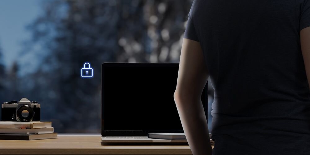 Mężczyzna w czarnej koszulce przy laptopie ASUS ZenBook z funkcją ASUS Adaptive Lock z niebieską ikoną kłódki i czarnym ekranem w tle okiennym - automatycznie blokuje system po jego odejściu