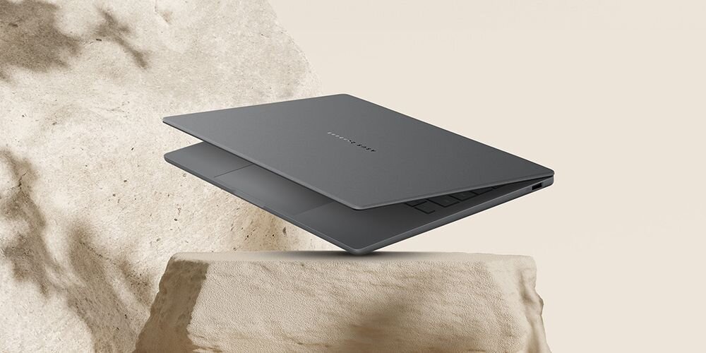 Laptop ASUS Zenbook w kolorze szarym unoszący się nad beżowym kamieniem z piaskowymi wzorami, minimalistyczna obudowa z precyzyjnym wykonaniem z aluminium - Minimalistyczna obudowa