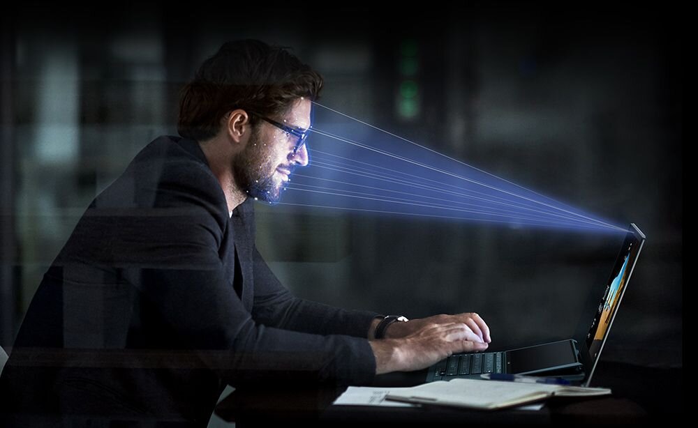 Mężczyzna pracuje na laptopie skupiony na ekranie w domowym biurze - Technologia rozpoznawania twarzy