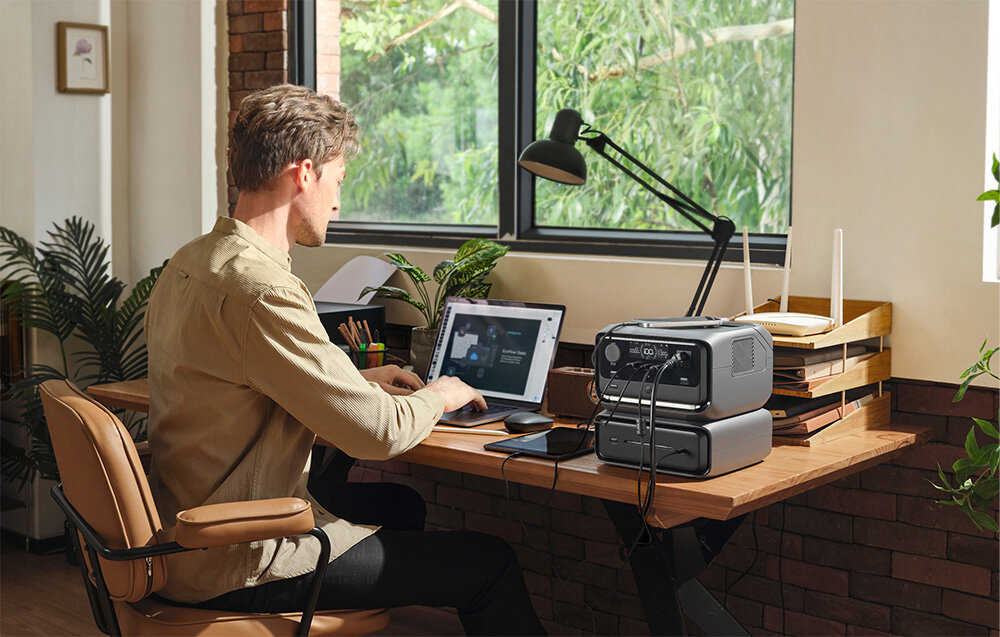 Stacja zasilania ECOFLOW River 3 Max 572 Wh Bank energii, Zalety technologii GaN, Mężczyzna pracuje przy biurku na laptopie, obok podłączony laptop do stacji zasilania