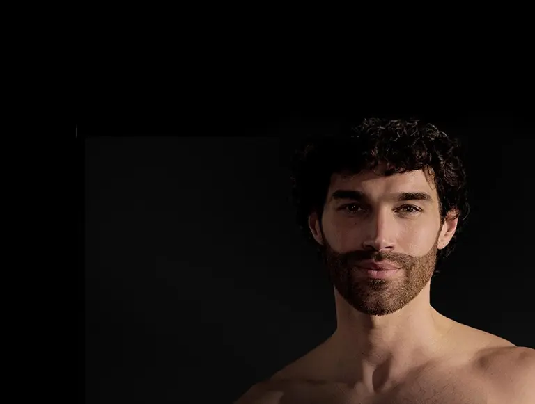 Mężczyzna w czarnej koszuli z uśmiechem na twarzy.