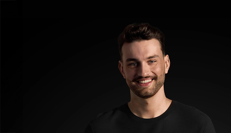 Mężczyzna w czarnej koszuli z uśmiechem na twarzy.