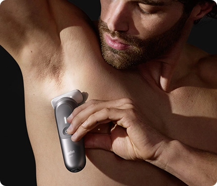 Mężczyzna używa maszynki Braun do golenia włosów pod pachą.