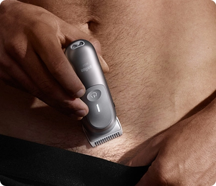 Mężczyzna golący okolice brzucha srebrną maszynką do ciała Braun.