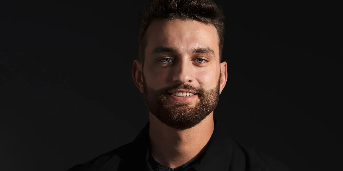 Mężczyzna w czarnej koszuli z uśmiechem na twarzy.