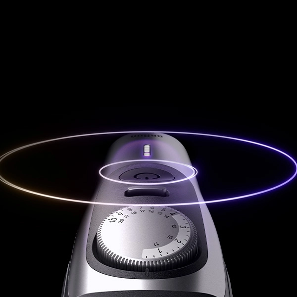 Srebrne pokrętło regulacji długości i podświetlony przycisk zasilania na górnej obudowie trymera Braun.