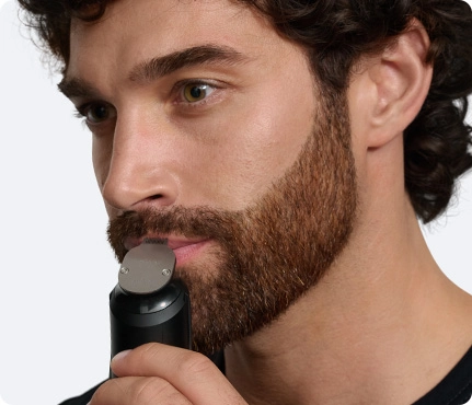 Mężczyzna golący okolice brzucha srebrną maszynką do ciała Braun.