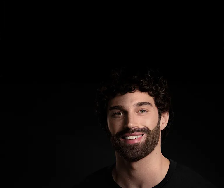 Mężczyzna uśmiecha się po goleniu, wyrażając radość i zadowolenie.