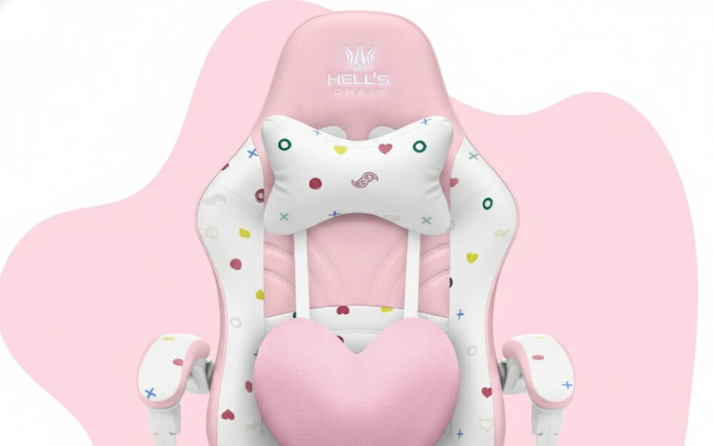 Fotel gamingowy w kolorach różowym i białym z kolorowymi wzorami, posiada poduszkę w kształcie serca oraz logo \'HELL\'S CHAIR\' na zagłówku.