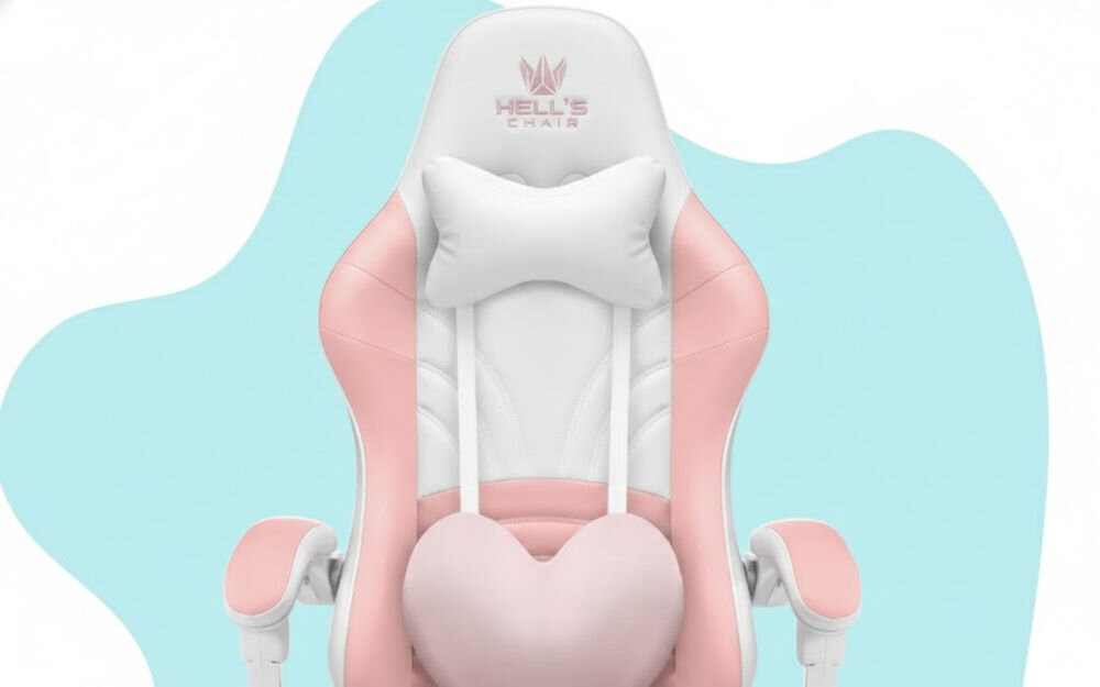 Fotel gamingowy w kolorze różowo-białym z poduszką w kształcie serca i napisem \'HELL\'S CHAIR\' na zagłówku. Tło jest jasnoniebieskie z białymi elementami.