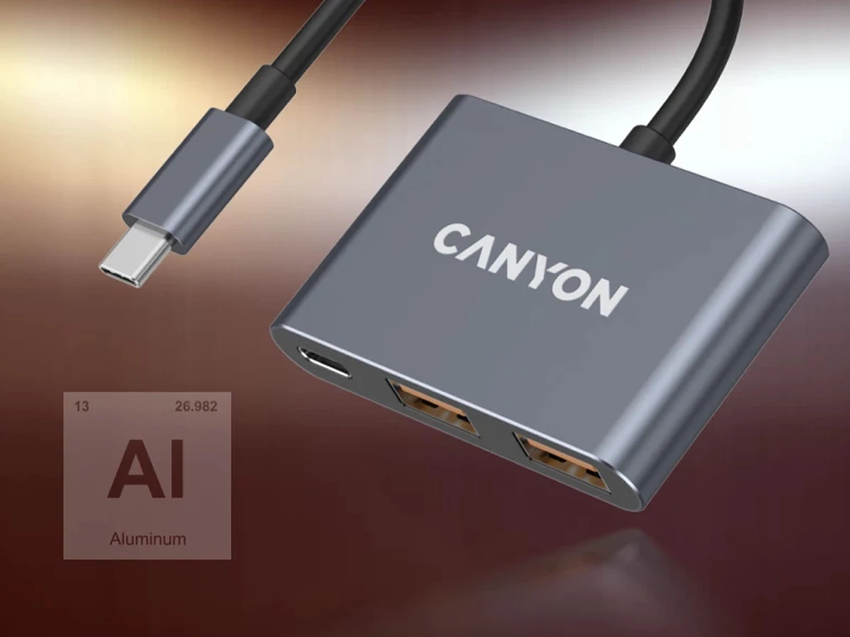Na obrazie widoczny jest ciemnoszary hub USB-C z logo \'CANYON\' oraz dwoma portami USB. W tle znajduje się symbol chemiczny \'Al\' z opisem \'Aluminum\'.