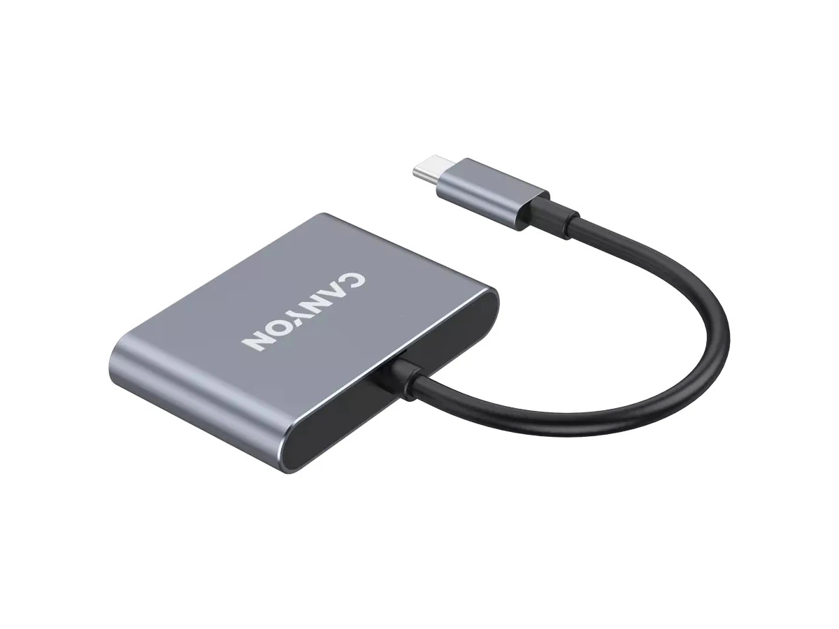 Na obrazie widoczny jest ciemnoszary hub USB-C z napisem \'CANYON\'. Urządzenie ma krótki kabel zakończony wtykiem USB-C.