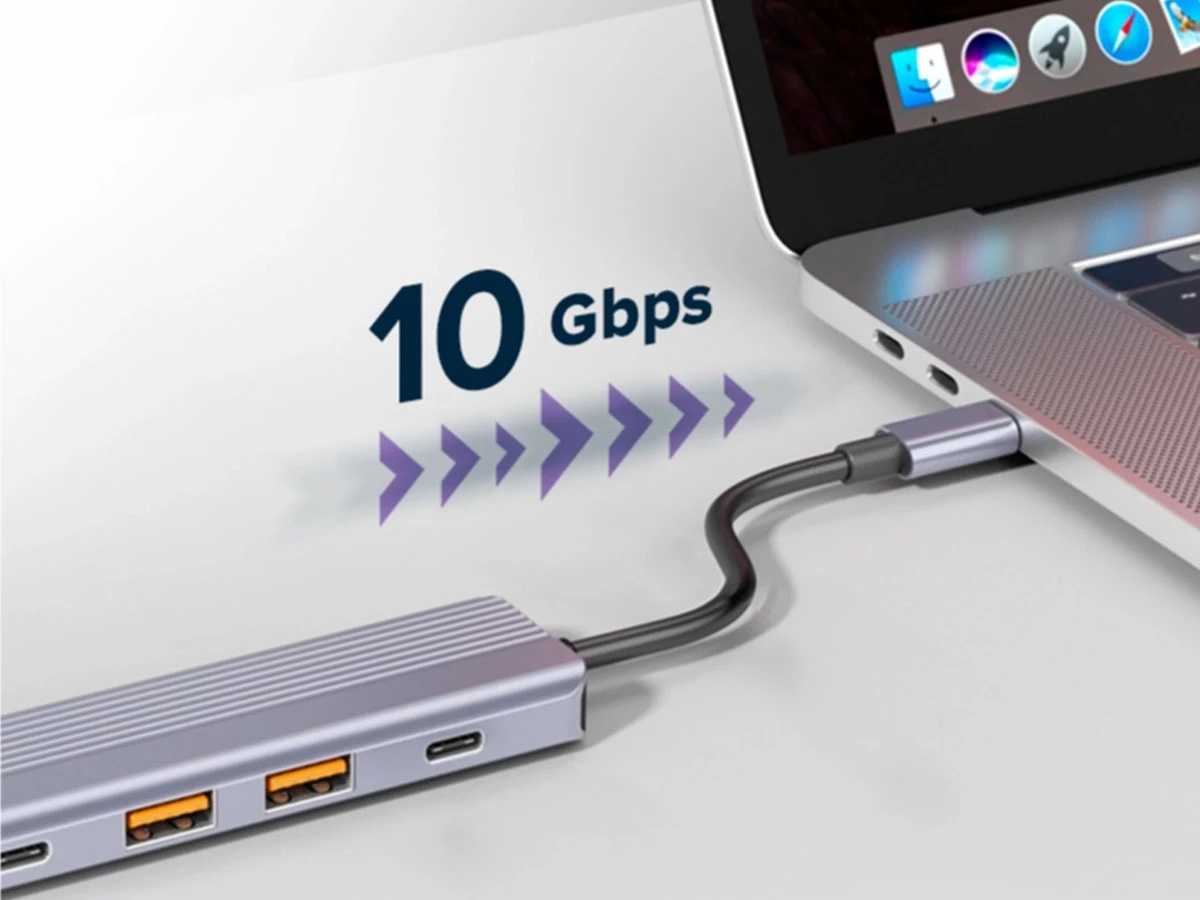 Szary hub USB-C podłączony do laptopa, z widocznymi portami USB i USB-C. Obok napis \'10 Gbps\' z graficznymi strzałkami wskazującymi na szybkość przesyłu danych.